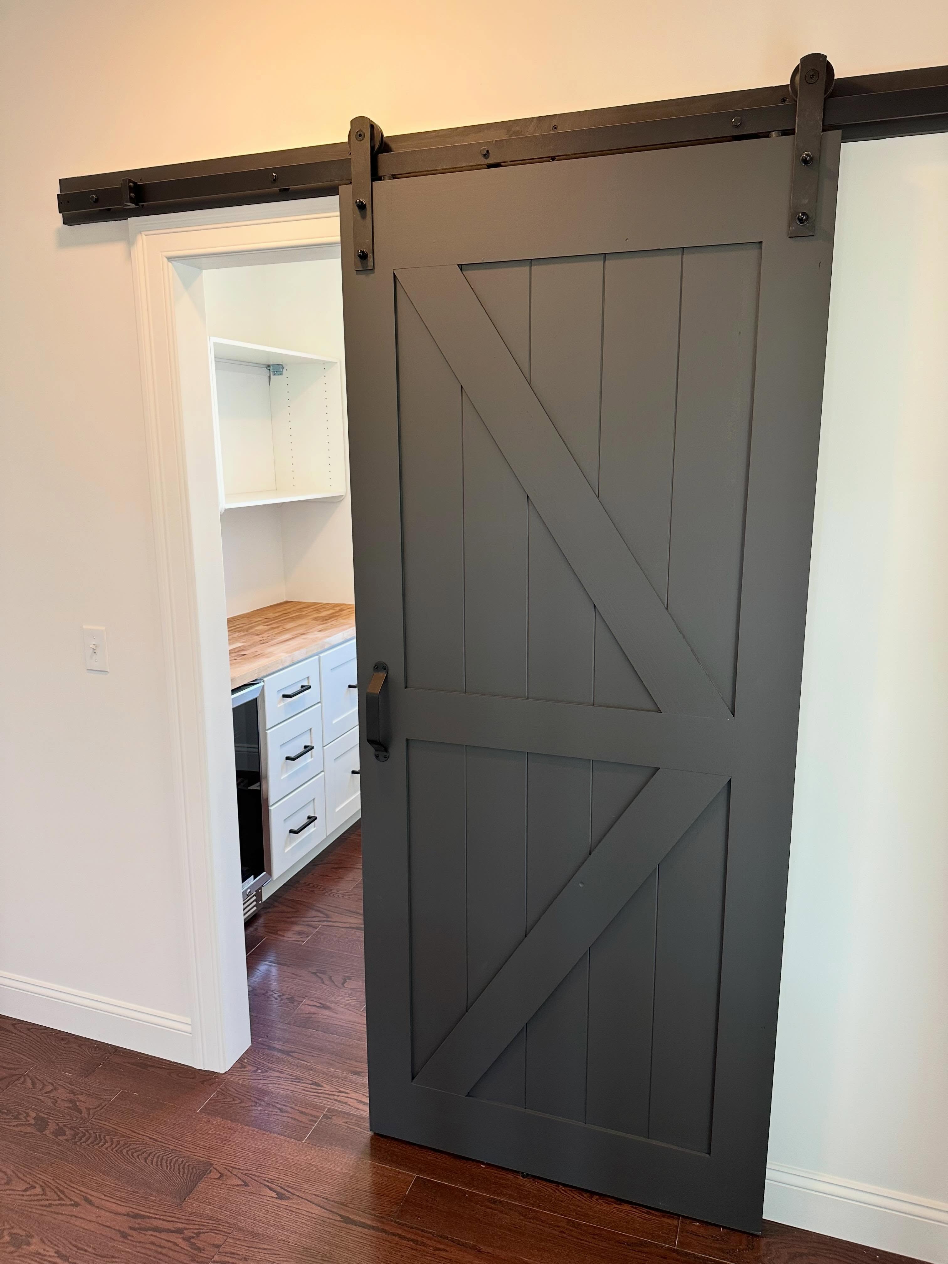 Gray barn door on pantry with butcher block counter