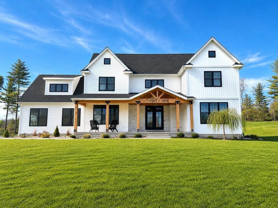 Completed white modern farmhouse with timber-frame front porch